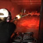 A person holding a gun in an indoor shooting range.