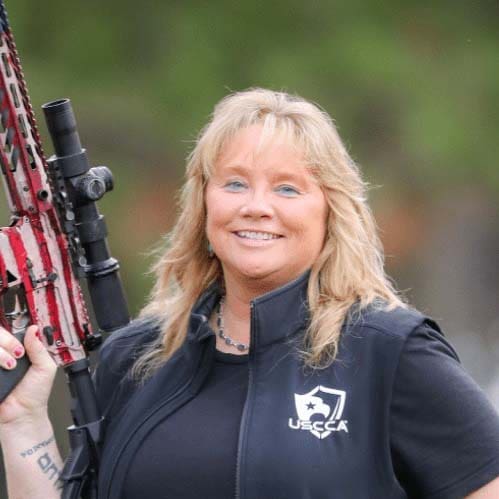 A woman holding a rifle in her hand.