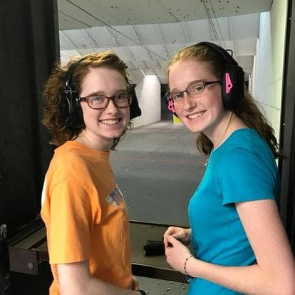 Two girls with headphones and a gun