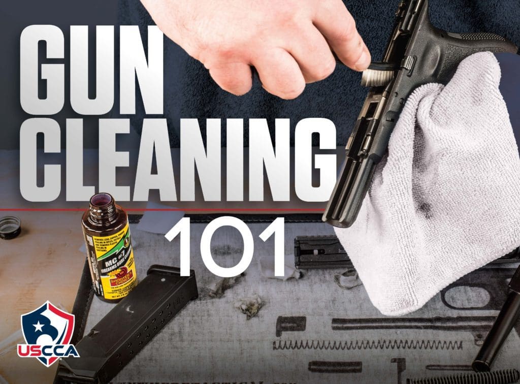 A person cleaning a gun with a spray bottle and some other items.