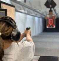 A woman wearing headphones and holding a gun