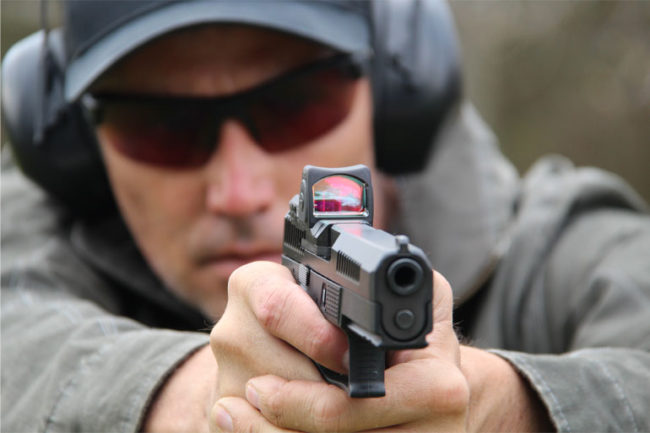 A man is holding his gun and aiming it.