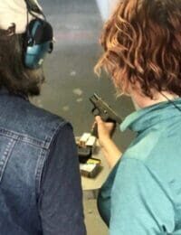 Two people are holding guns and wearing ear muffs.