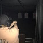 A person is shooting at targets in an indoor gun range.