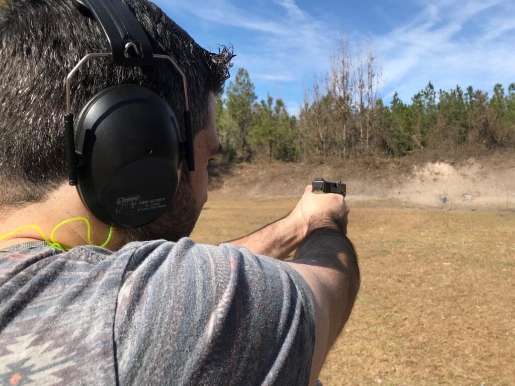 A man wearing ear muffs and holding a gun.