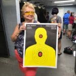 A woman holding up an nra target at the range.