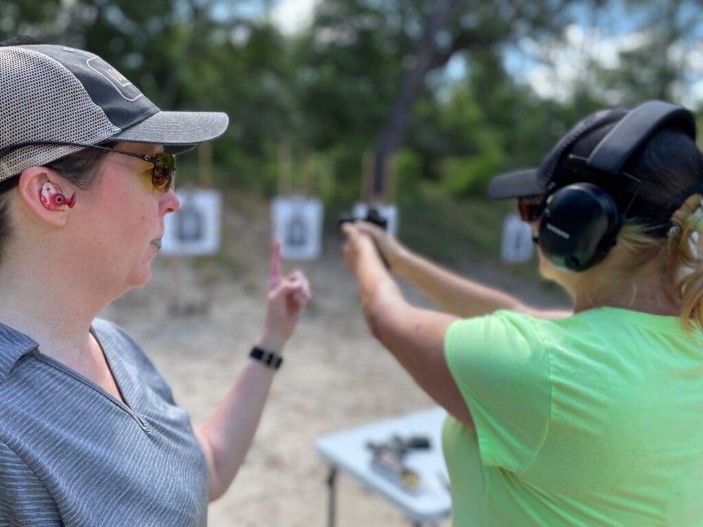 A woman pointing at another person with a gun.