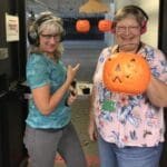 Two women are posing for a picture with pumpkins.