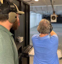 A man and woman are shooting at an indoor target.