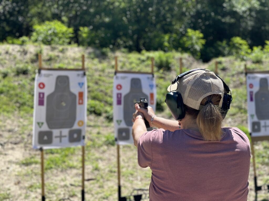 A woman is holding her gun up to the side of her face.