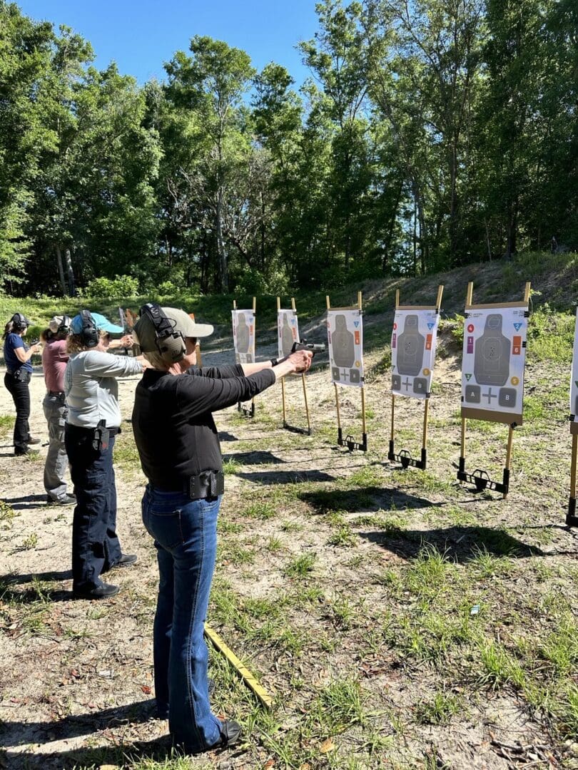 A group of people standing around aiming guns at targets.