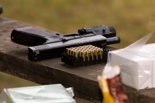 Handgun and ammunition on wooden table.
